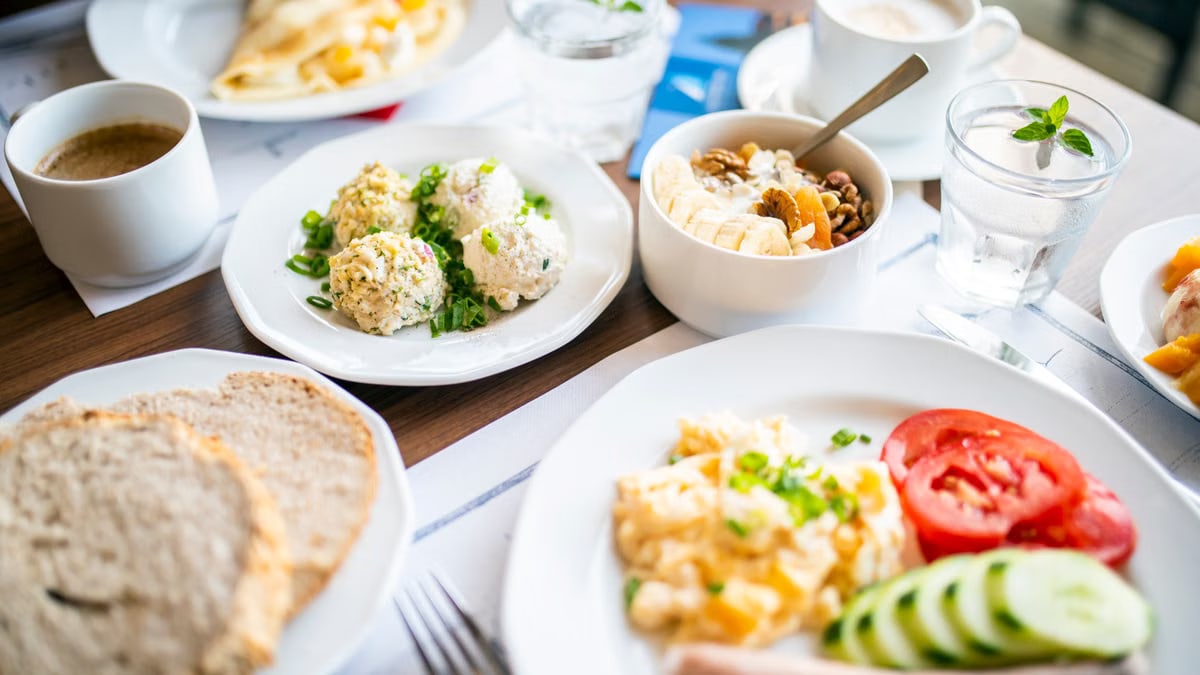 From above of tasty brunch of power bowl and scrambled eggs with fresh vegetable slices against drinks on table